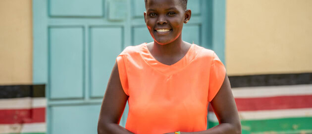 A woman stands outside smiling to the camera