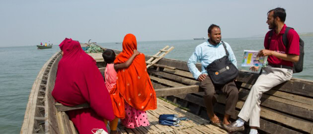 Four people sit in a wooden boat on the water.