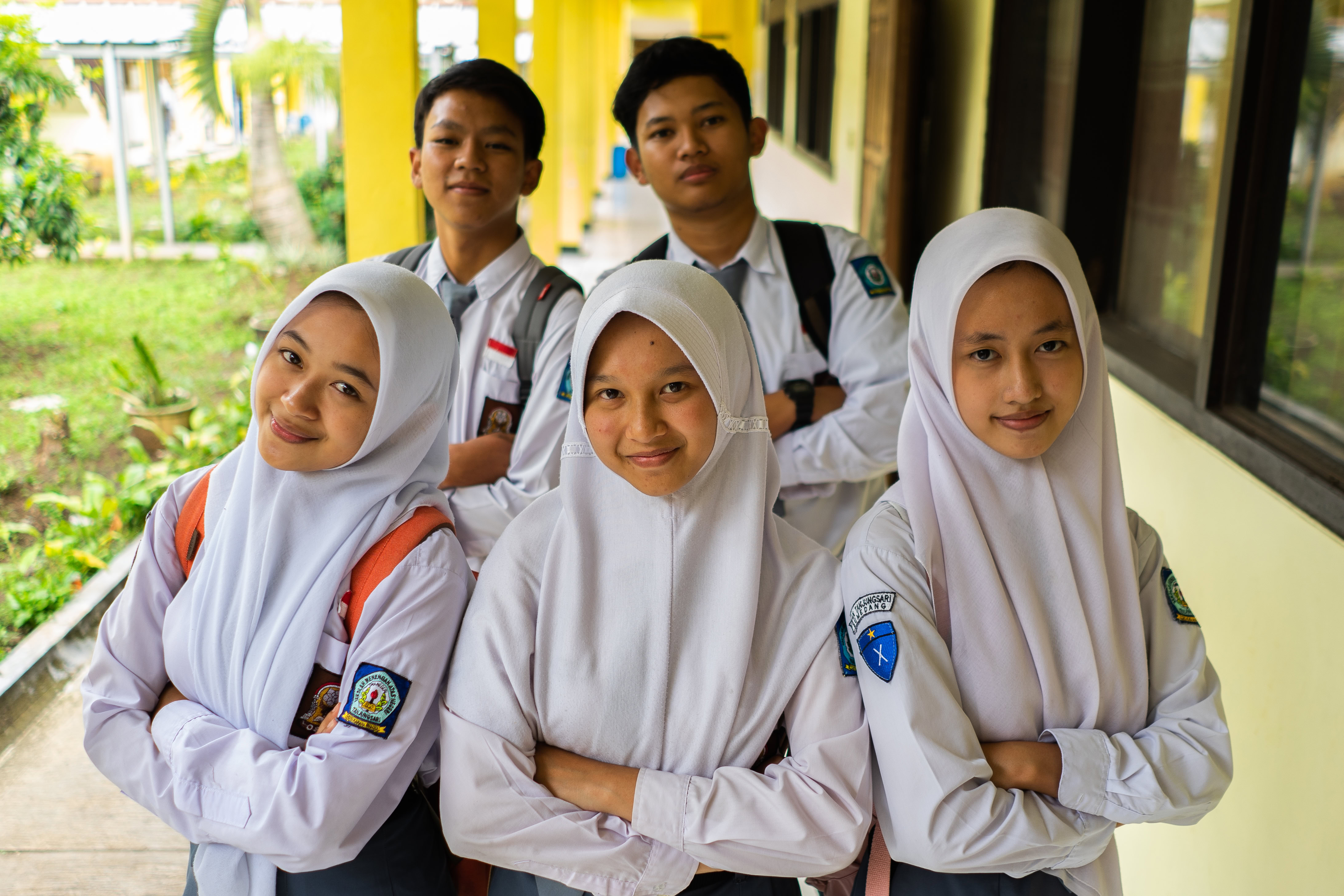 Teenage girls in Indonesia smile to camera in their school uniforms.