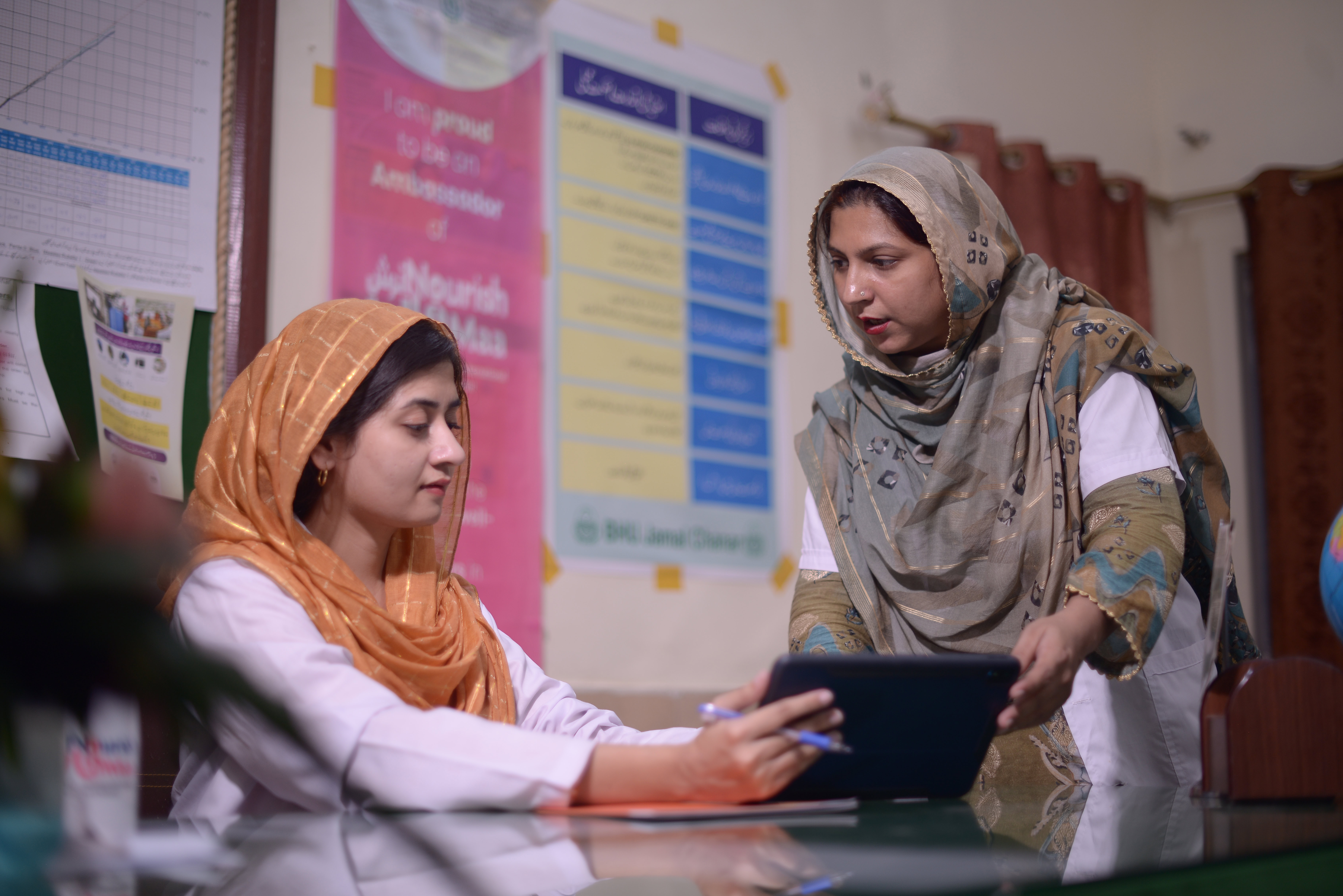 A woman explains something on a computer screen to another person.