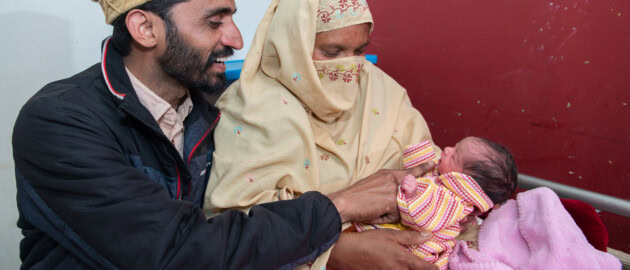 A couple looks lovingly at their newborn baby.