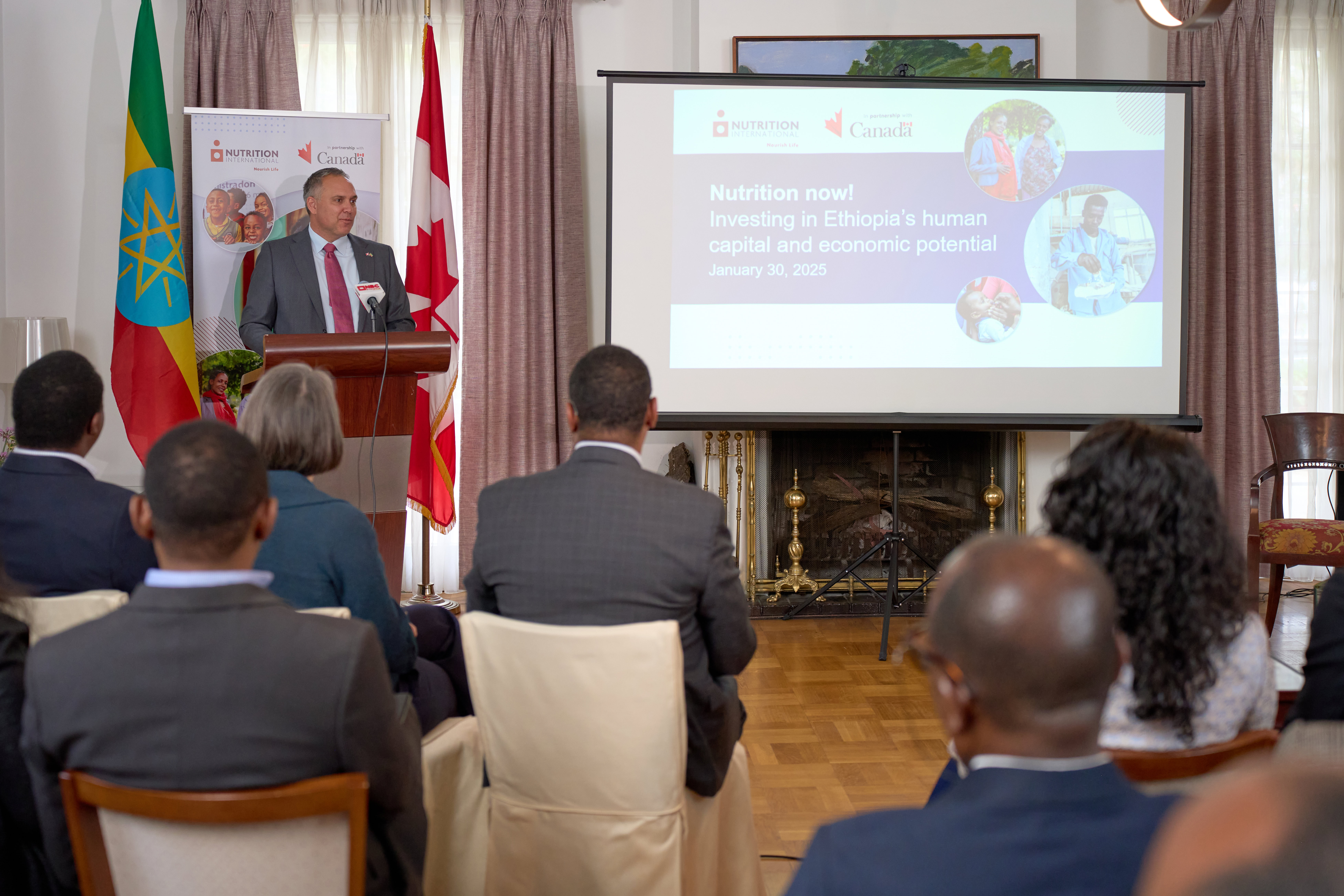 A room of people sitting watch a presentation.