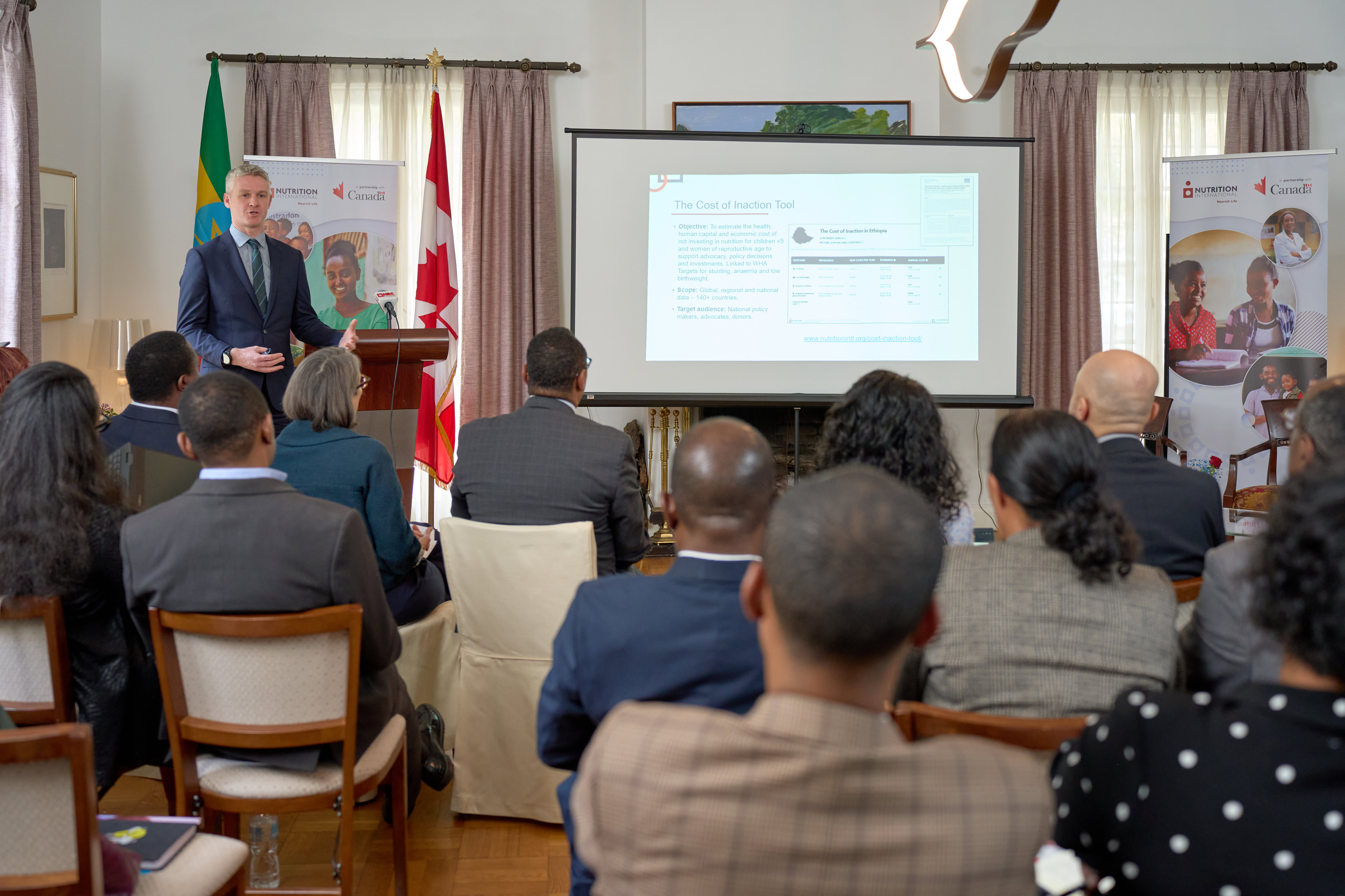 A man stands in front of a screen delivering a presentation.