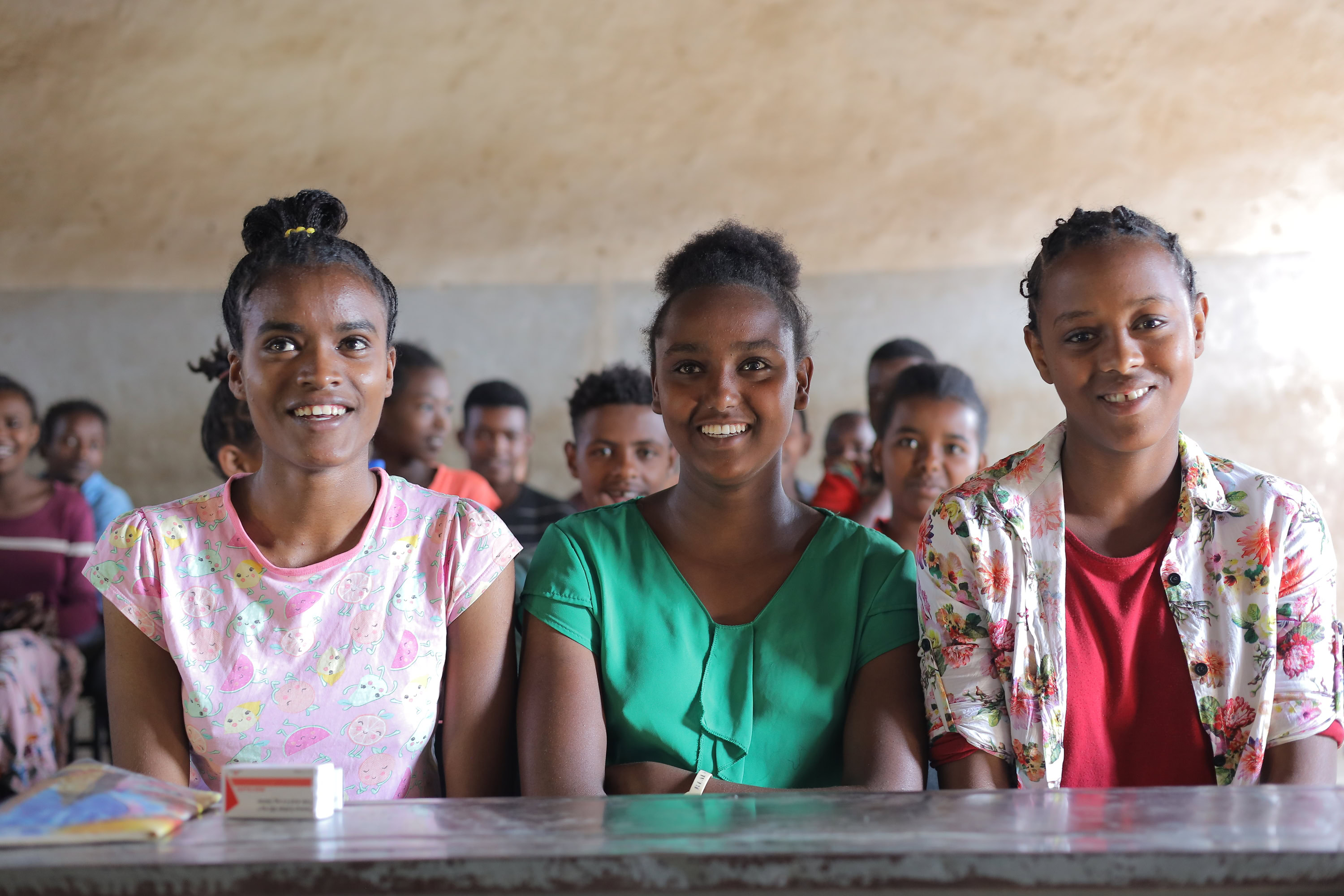 Three adolescent girls in a school classroom in Ethiopia.