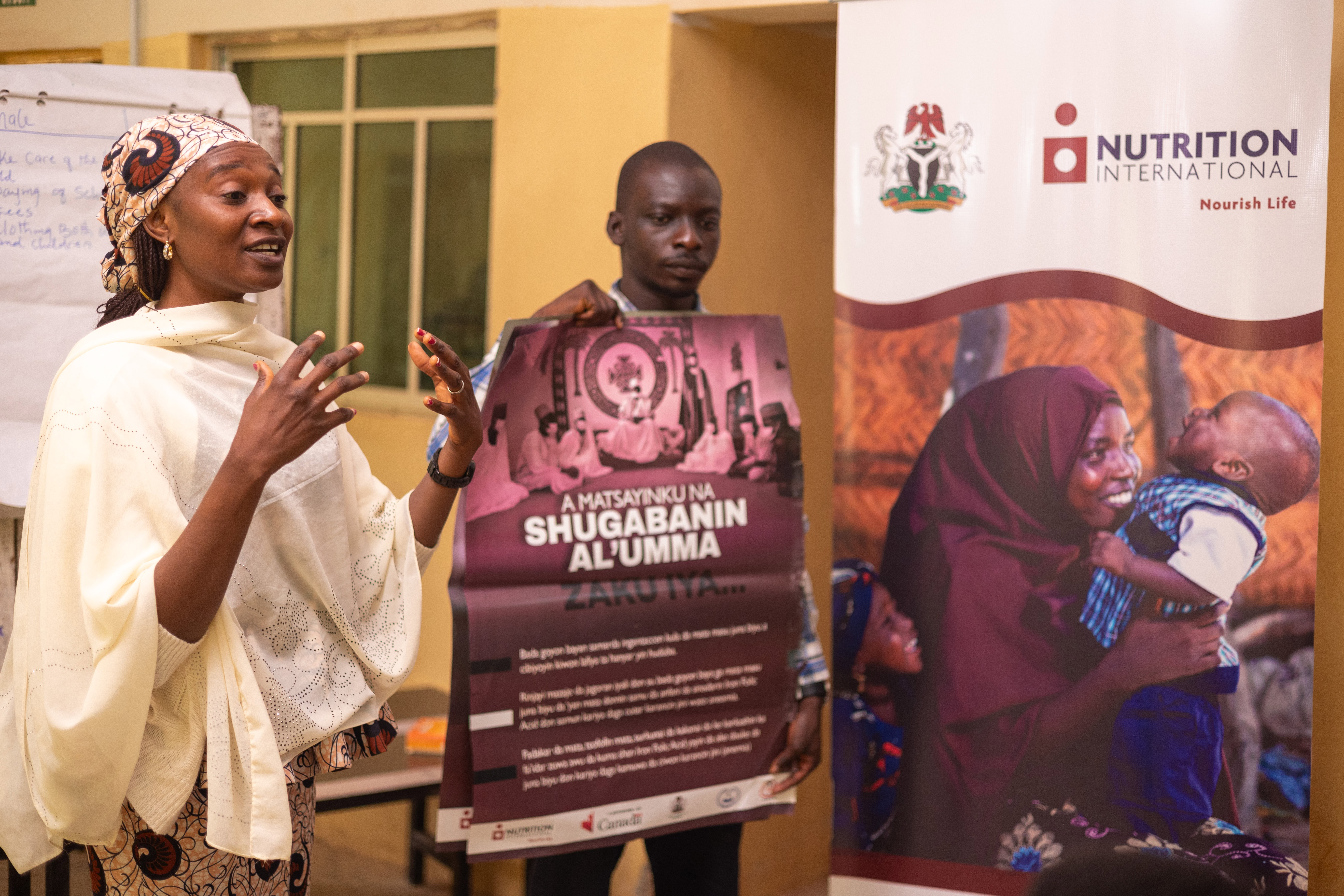 A woman speaks and gestures with her hands leading a presentation on maternal health.