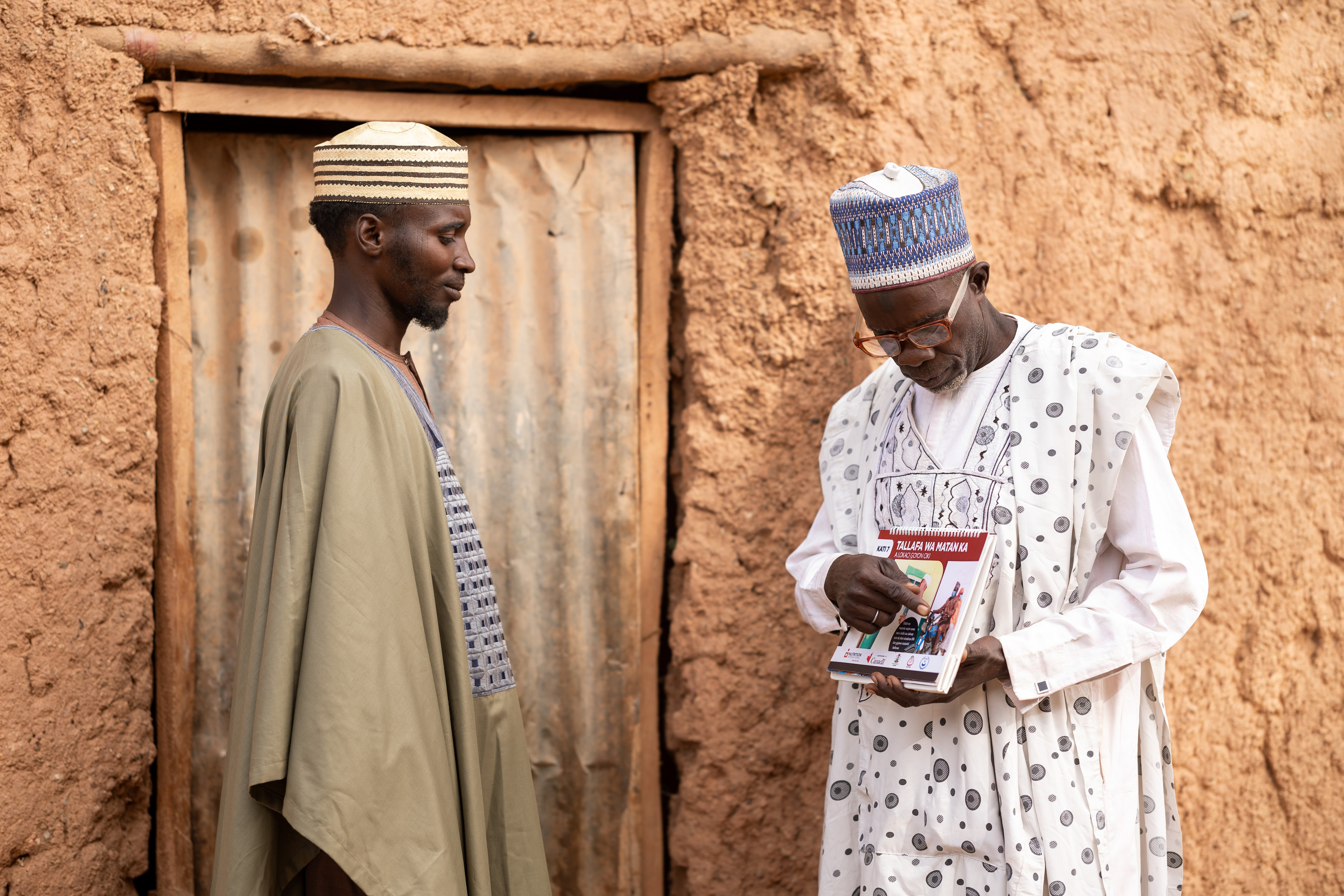 Two men greet each outside of one of the man's homes.