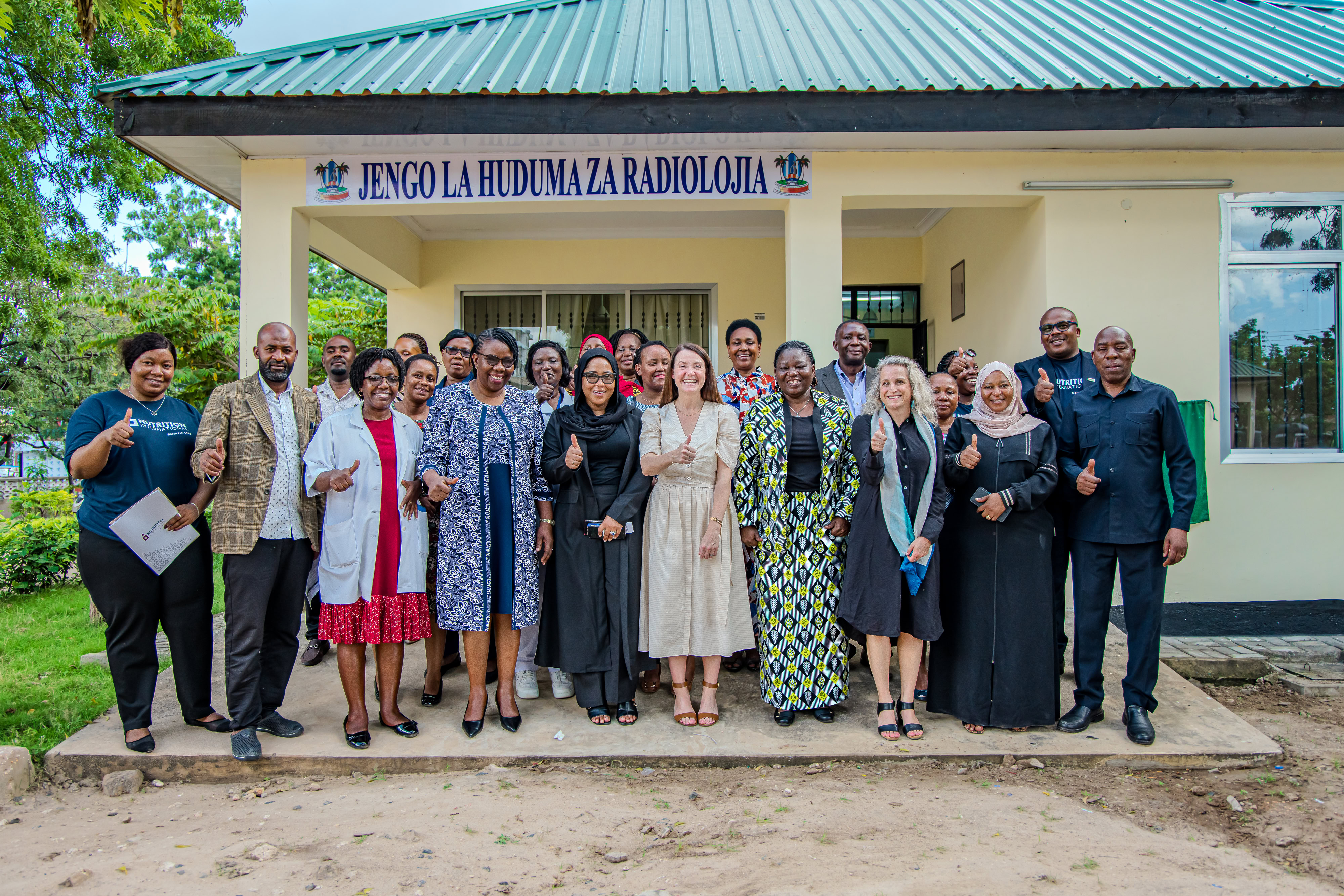 A group of people stand in front of a building facing the camera smiling