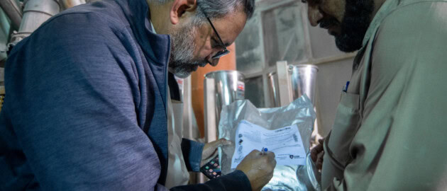 Nutrition International staff and a miller examine a package for wheat flour fortification in Pakistan