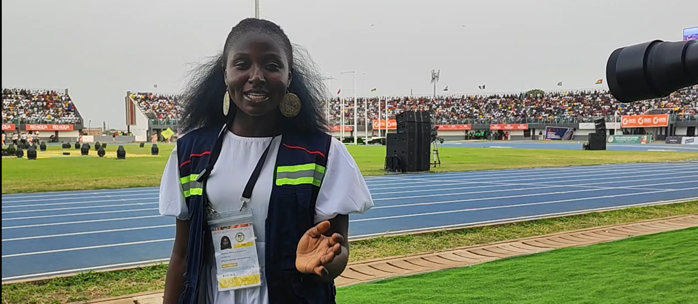 A woman standing and hosting a closing ceremony at sporting event.