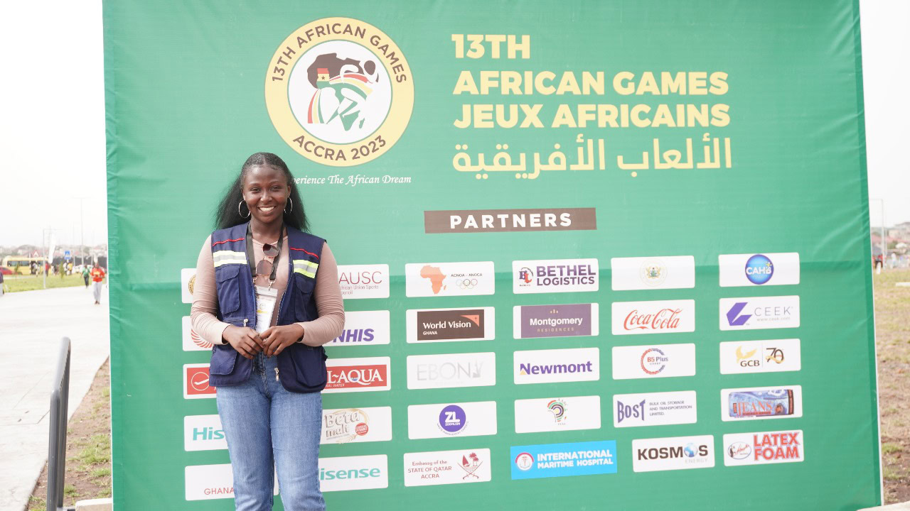 A woman standing in front of sporting event sign.
