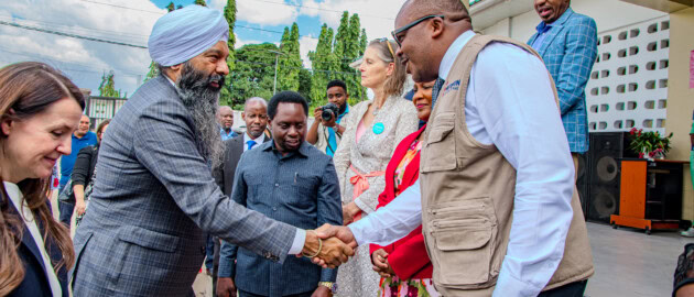 Two men shaking hands in a group of people.
