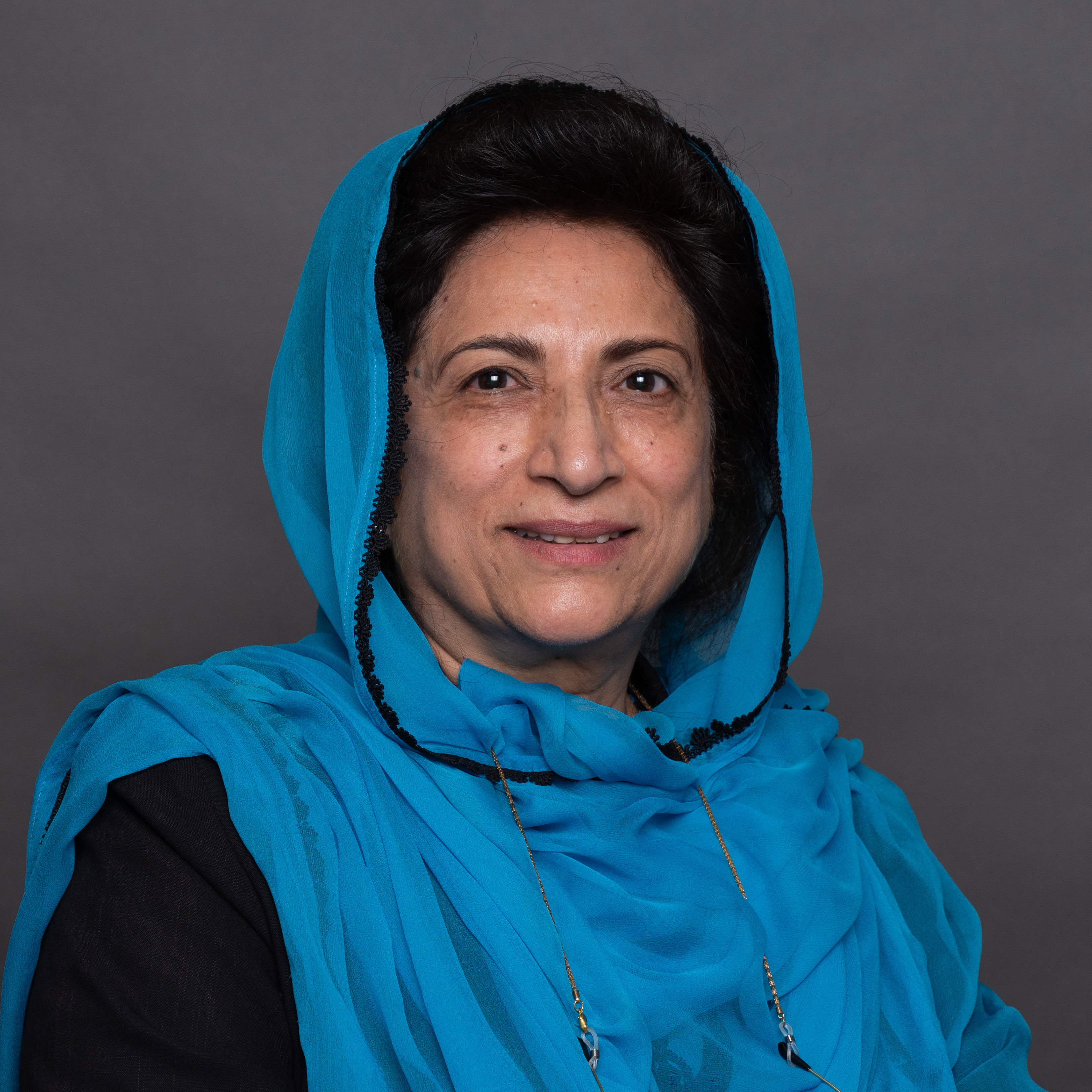 A woman smiling to camera wearing a blue scarf