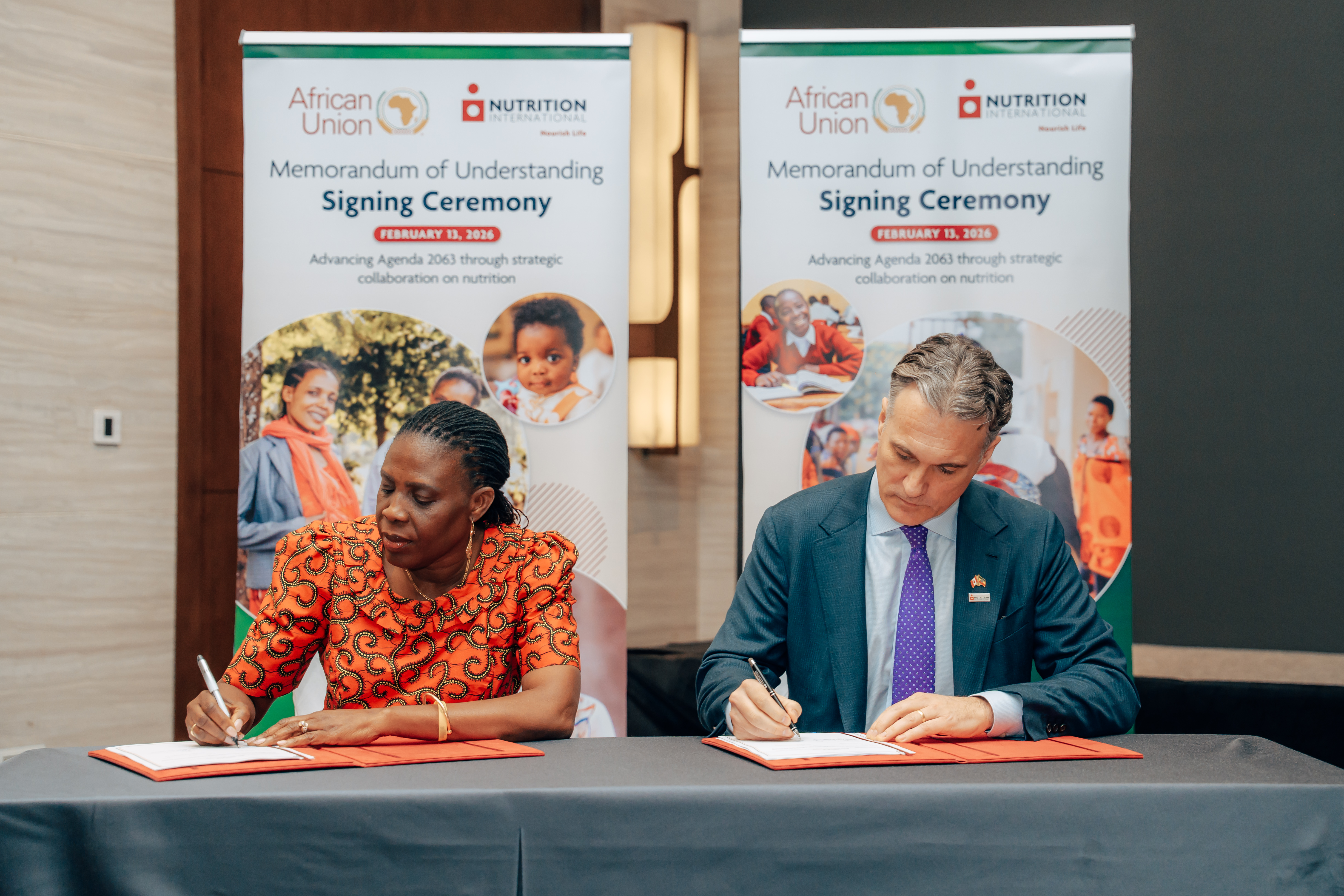 A man and woman sit signing a document