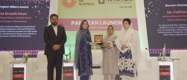 A woman leader accepts an award in Pakistan. There are four people on stage.