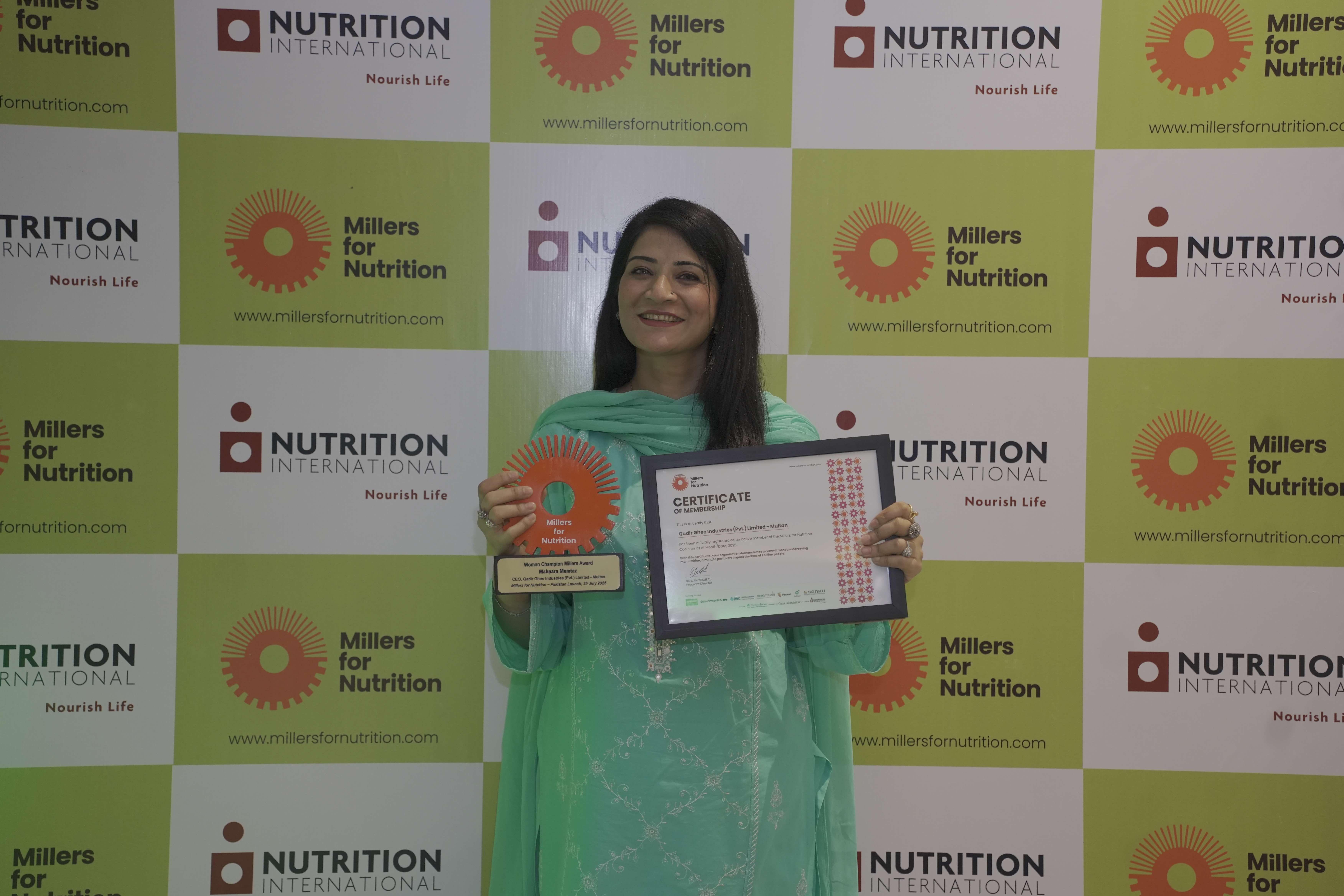A woman stands holding a certificate as an award winner at the Nutrition for Millers launch in Pakistan.