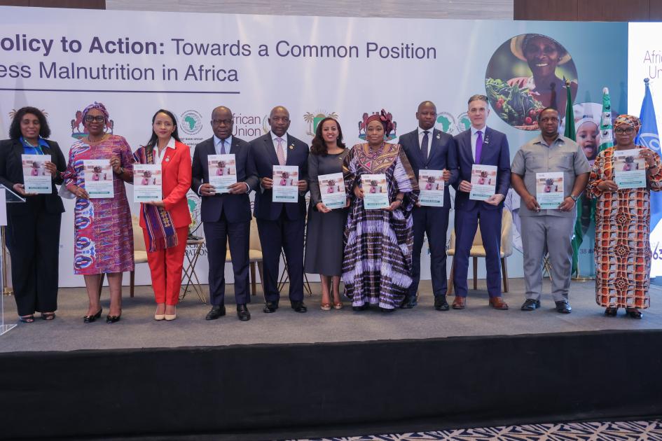 A group of people stand holding a document up