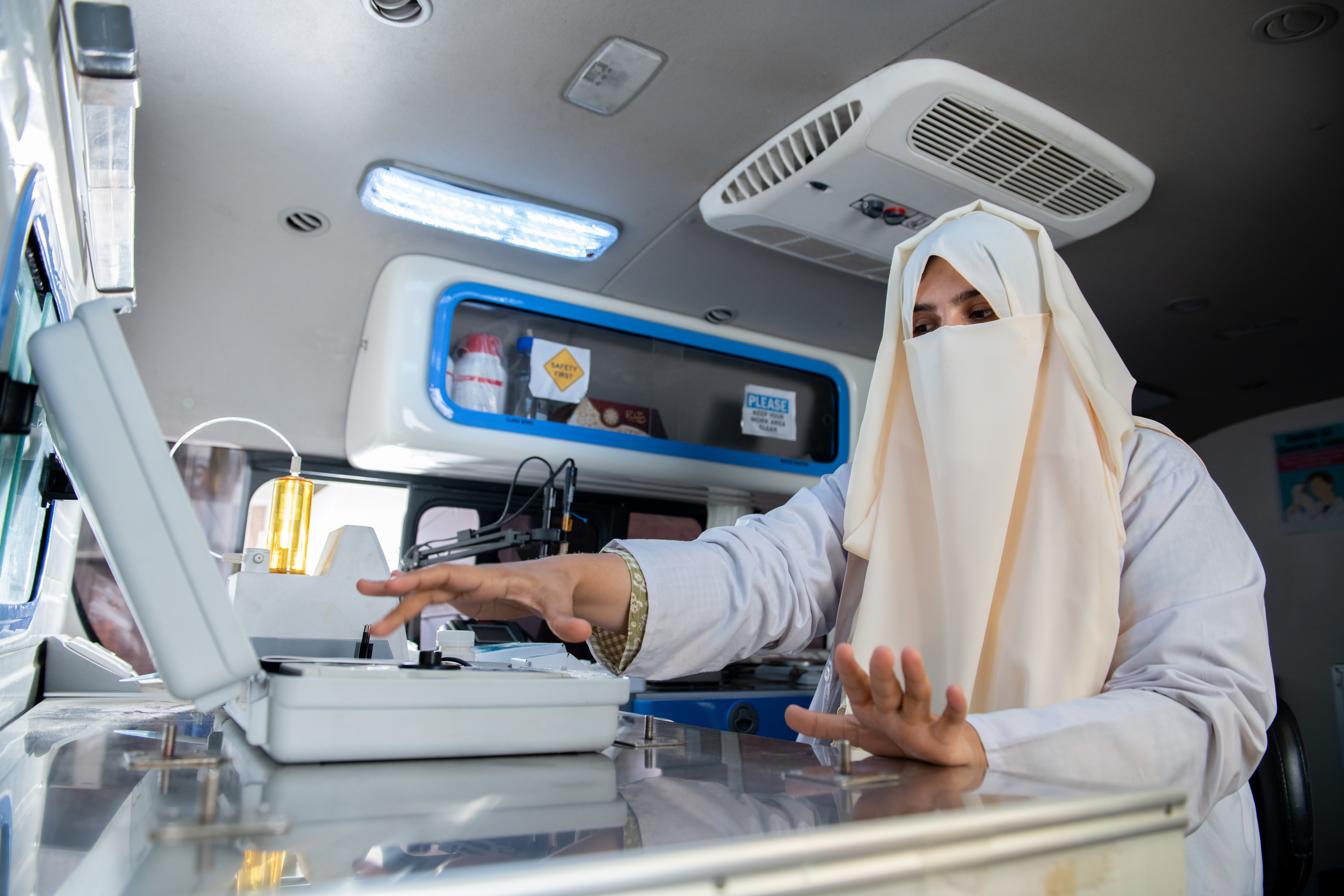 A woman sits inside a mobile lab and is checking the quality of fortified edible oil.