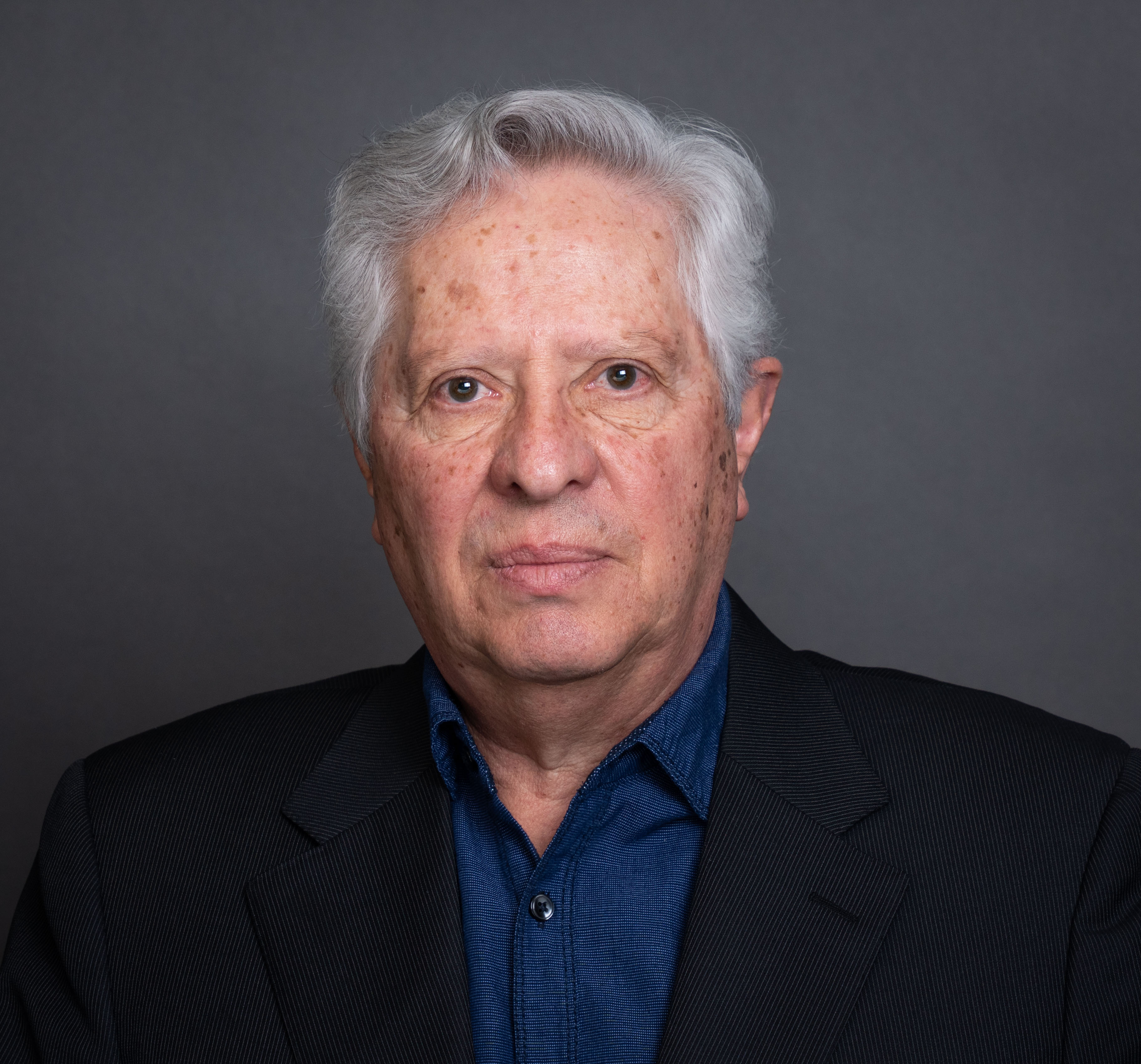 A male in a dark suit faces the camera